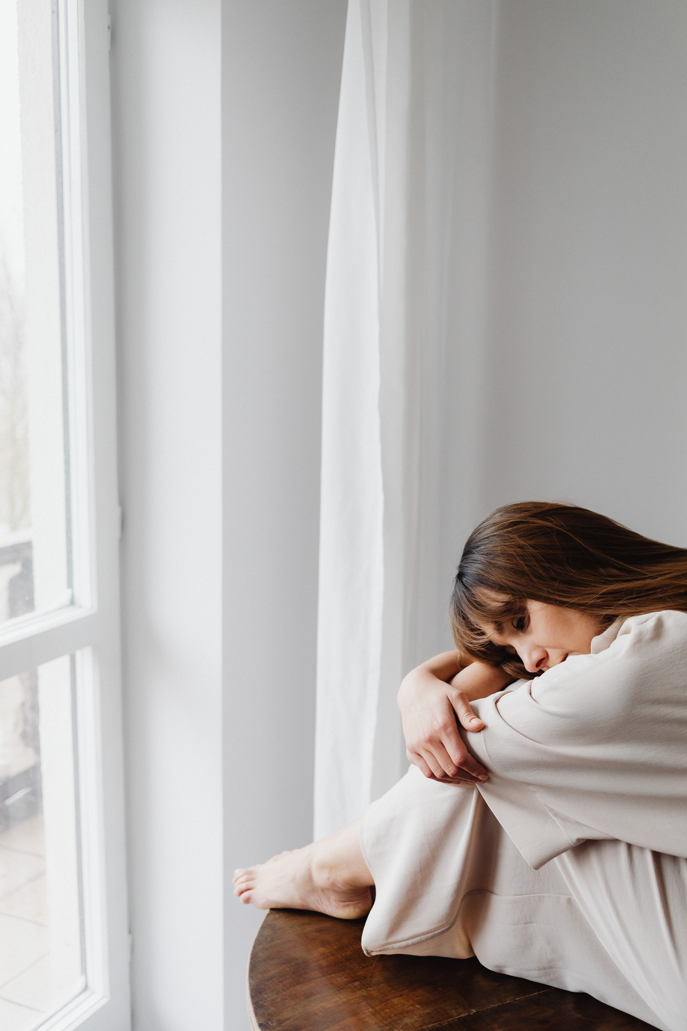 Sad Woman on Table near Window